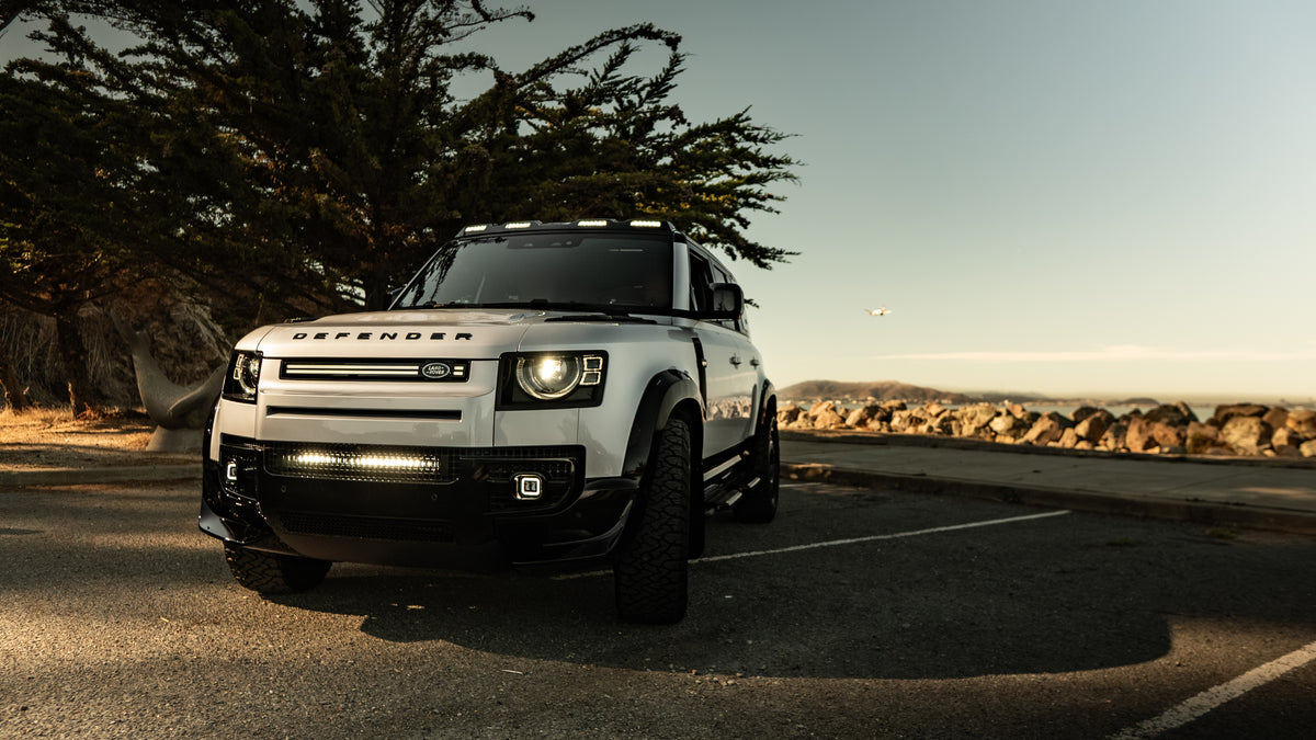 White Land Rover Defender with roof lights, side steps and premium styling accessories